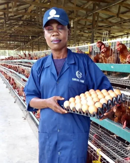 The co-founder in a Caritana Farms smock holding a tray of eggs in the laying house